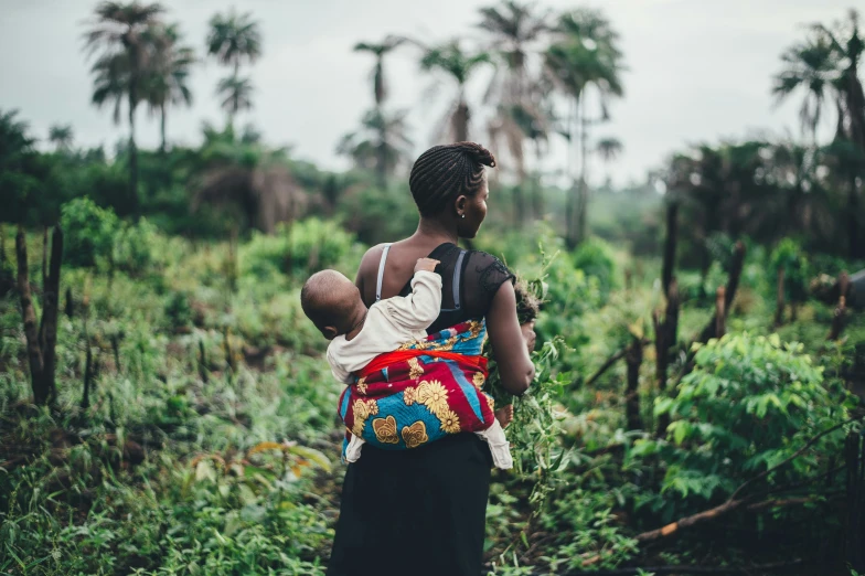 woman holding a baby in a colorful bag