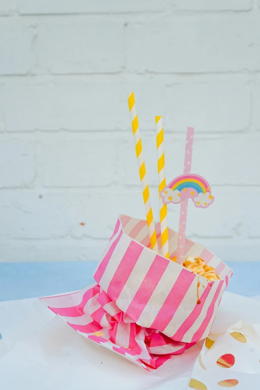 pink and yellow striped paper shopping bag and two striped cups