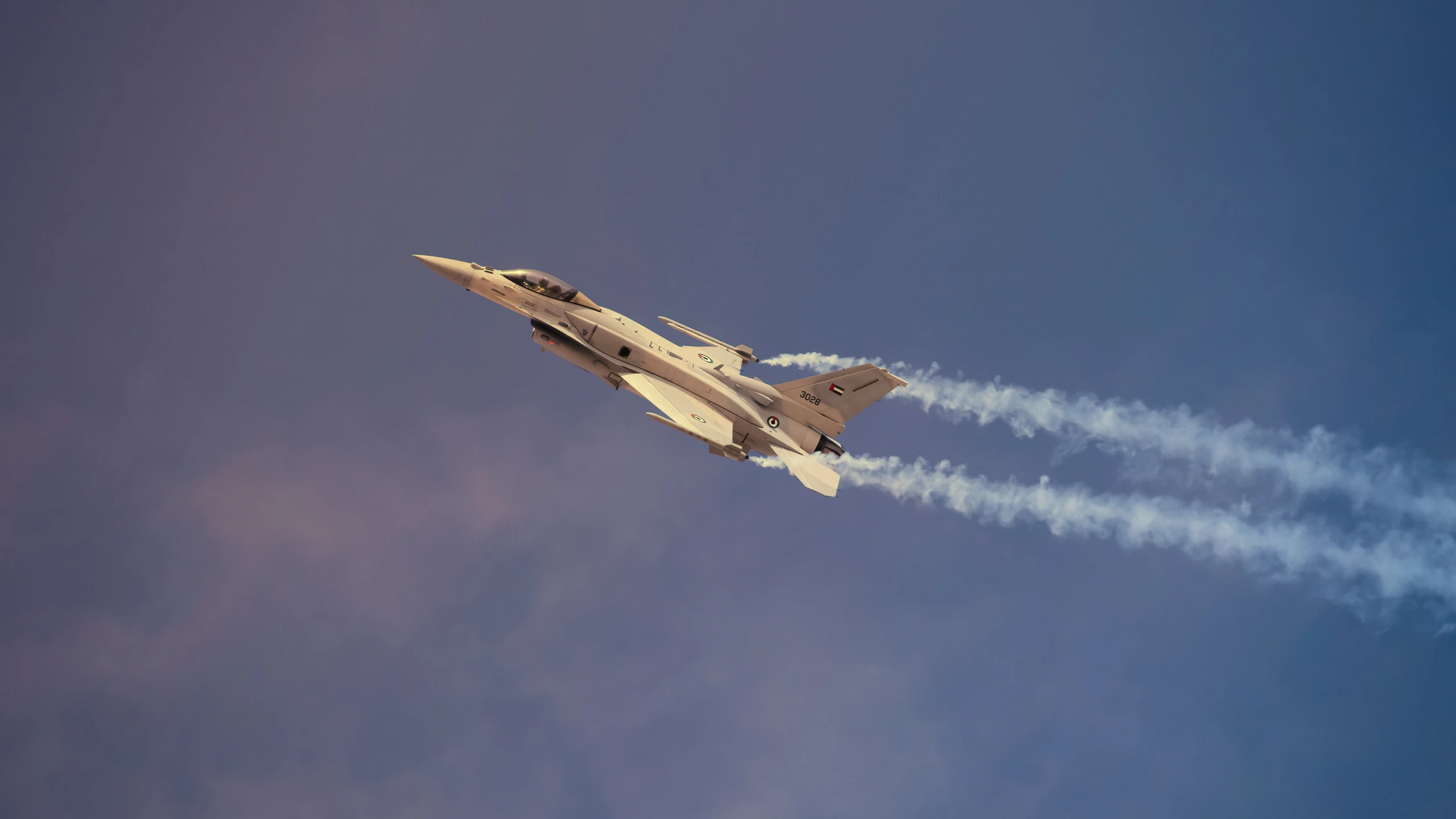 a fighter jet in a cloudy sky with three smoke trails