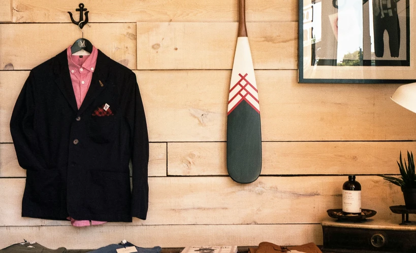 an old - fashioned suit and sweater hang on a wall