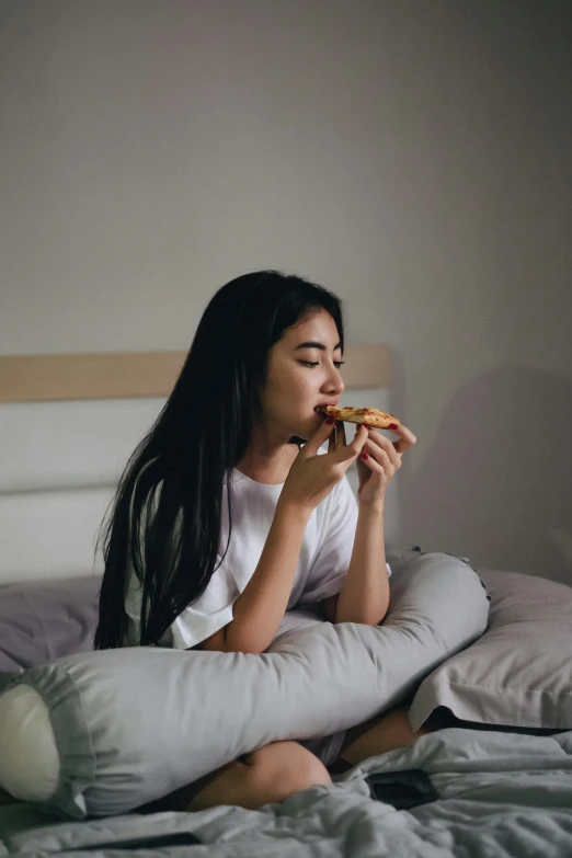 a woman sitting on her bed eating food