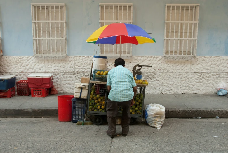 a person standing with an umbrella near a produce cart