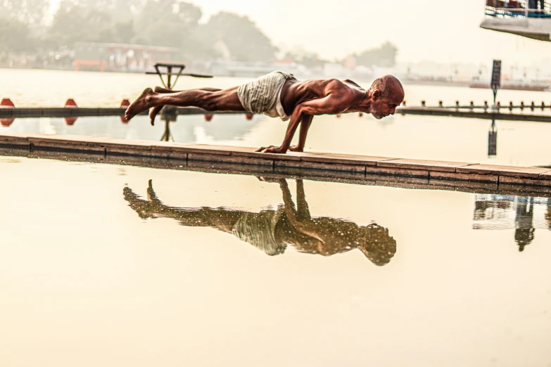 the man is doing some swimming tricks by the water