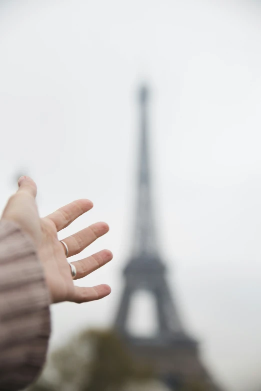 a persons hand with the eiffel tower in the background