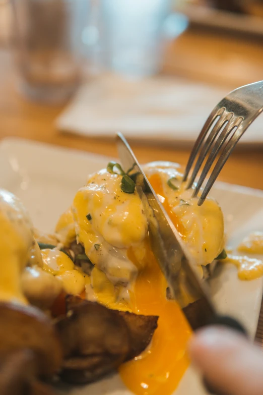 someone uses a fork to eat food on a plate