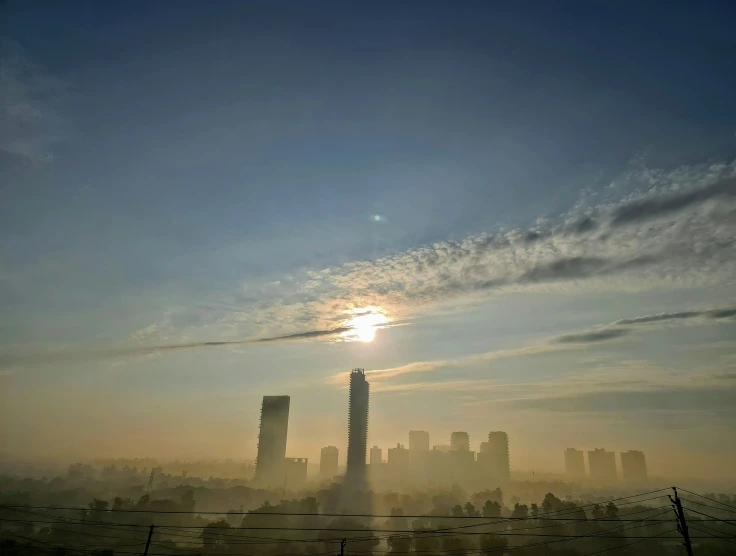 the sun is setting over a city in a hazy sky