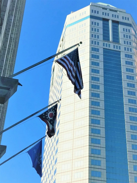 two american flags and one blue flag in front of an office building