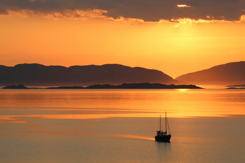 a boat sitting on top of a body of water at sunset