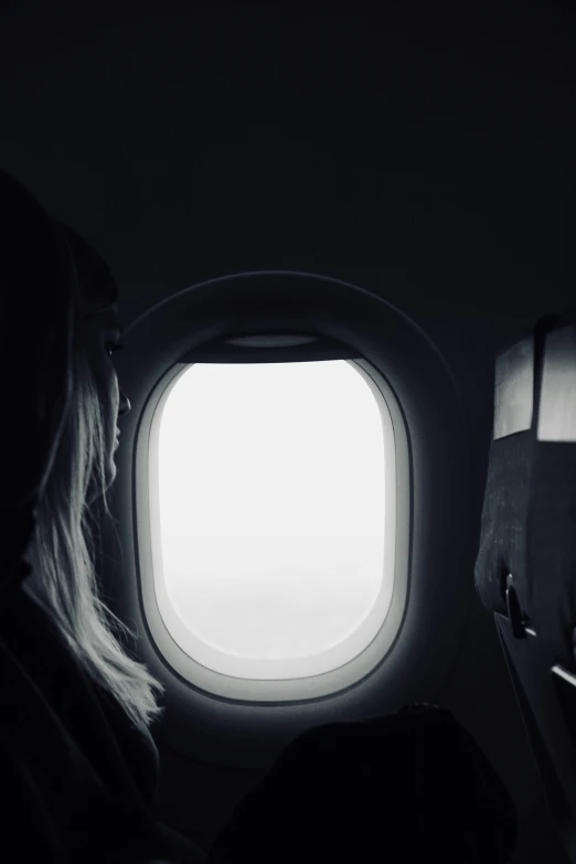 a person sitting by an airplane window and looking at soing