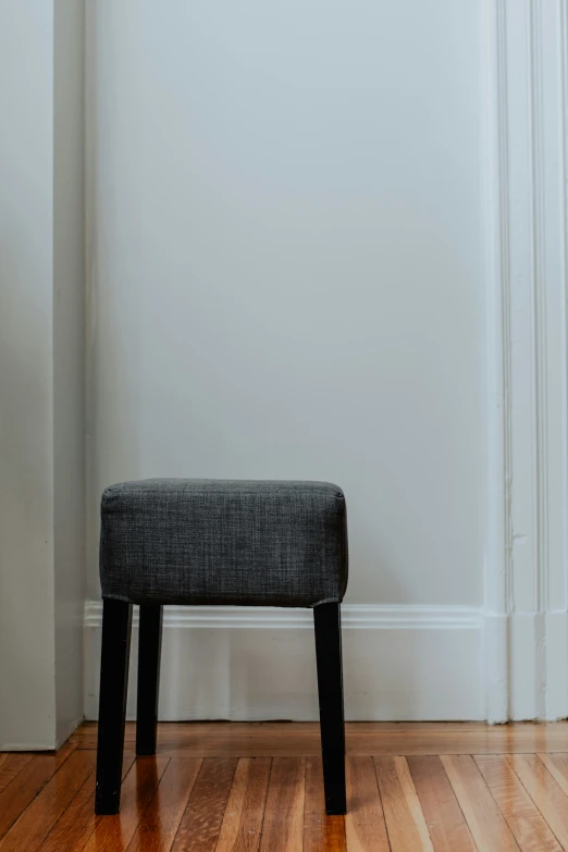 a simple bench sits alone in front of the white wall