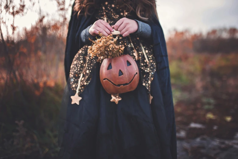 woman in long dress holding pumpkin bag wearing star decorations