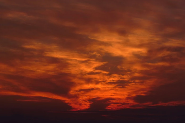 an orange sunset with clouds in the sky