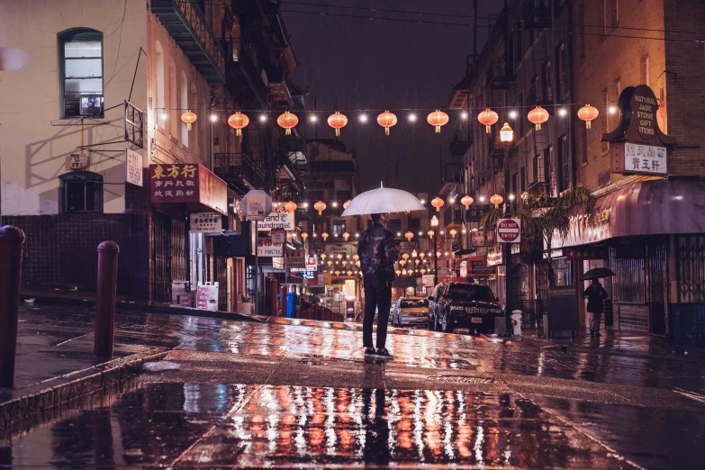 a man standing on a rain covered street holding an umbrella