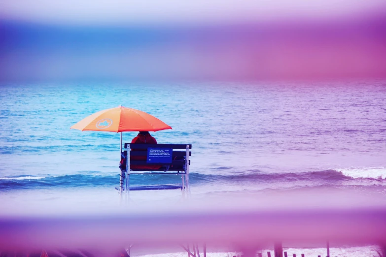 the person is on his back sitting under an umbrella