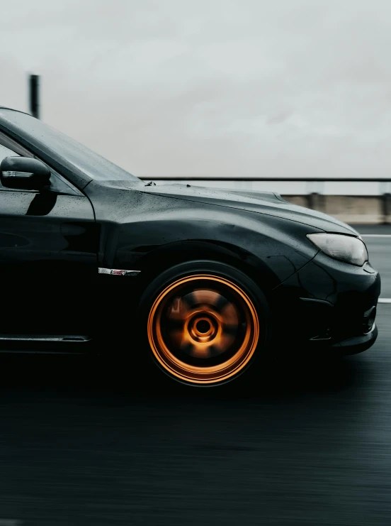 a car driving down the road with orange rims