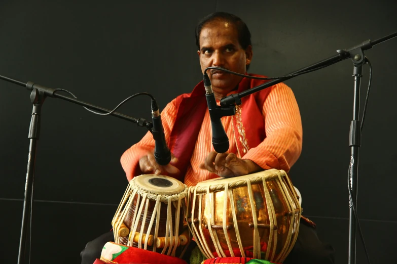 a man sitting in front of a microphone holding onto two instruments