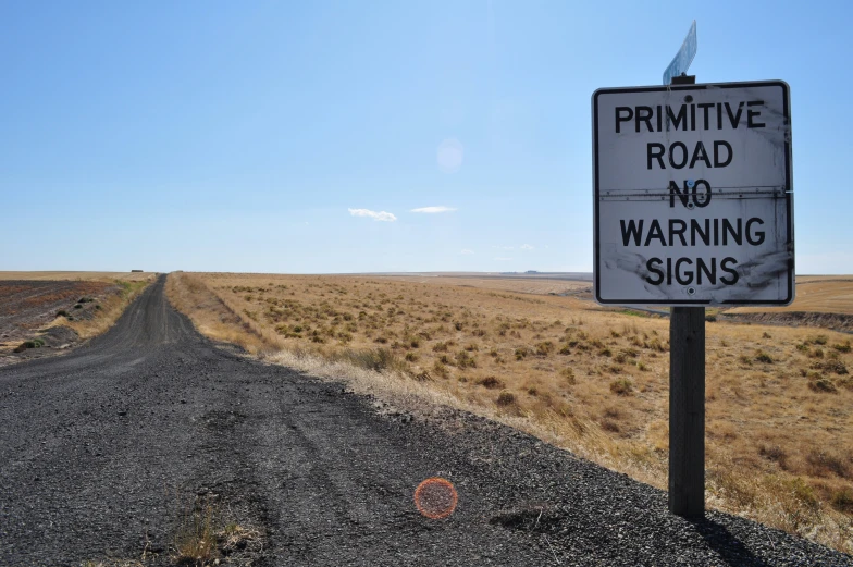 a road sign on an open empty dirt road