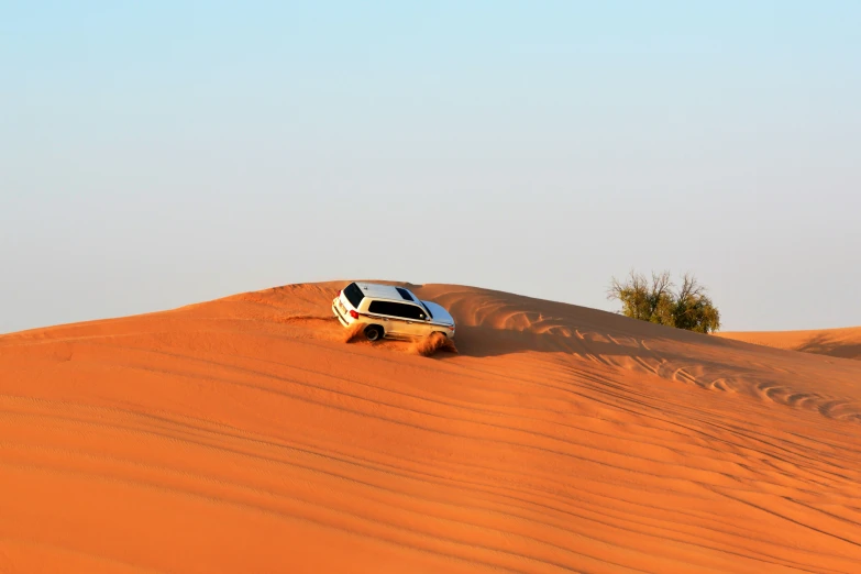 an suv driving in the desert on sand dunes