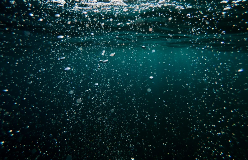 a blue ocean with bubbles and a black background