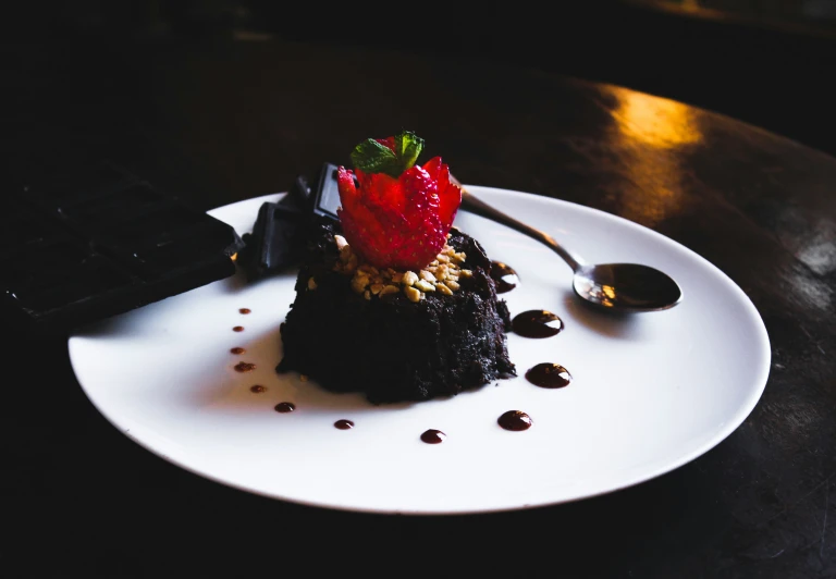 a piece of dessert on a plate with chocolate and a strawberry
