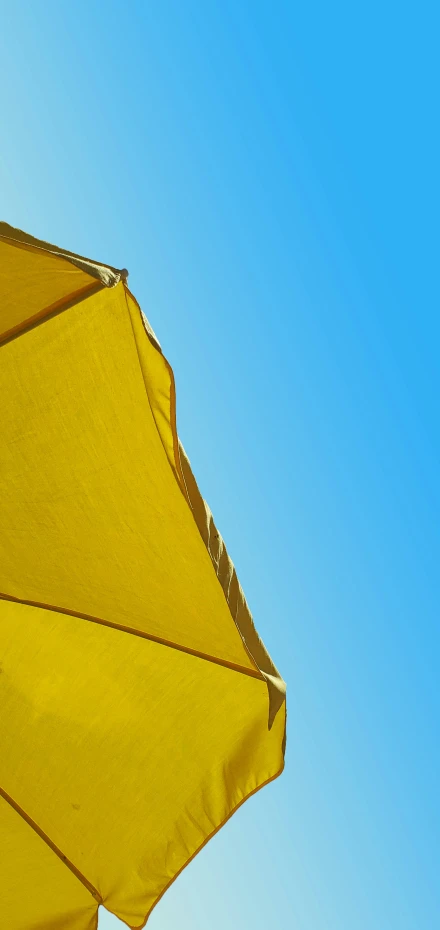 a yellow umbrella that is over a blue sky