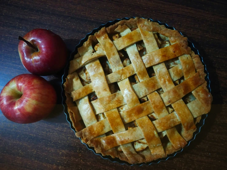 two apples sitting next to a pie in a bowl