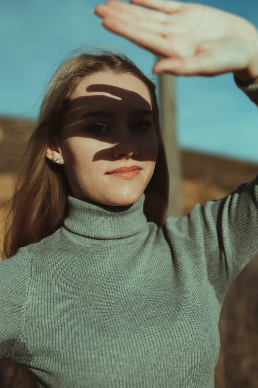 the girl poses outside, her hands on top of the face