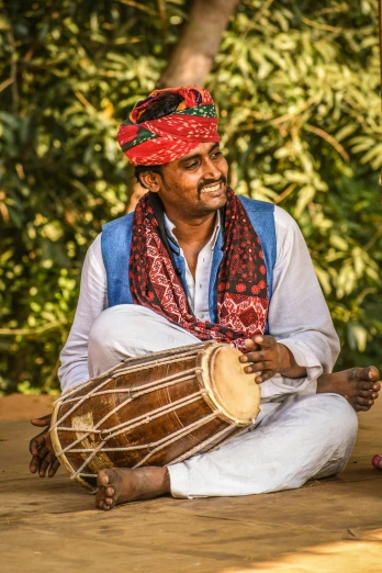 an indian man playing a congnar on the ground