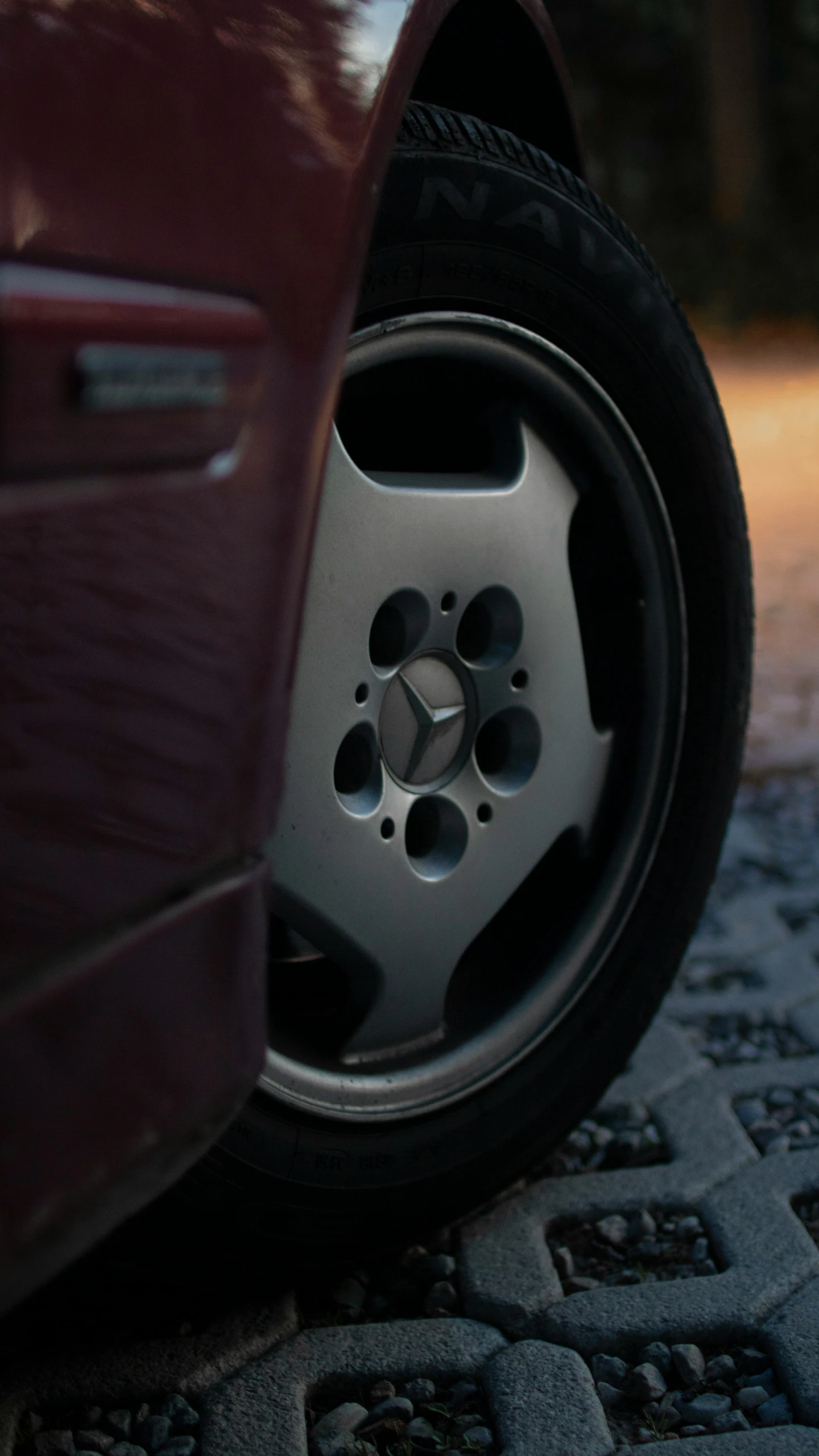 the tire of a red car that is parked on a street