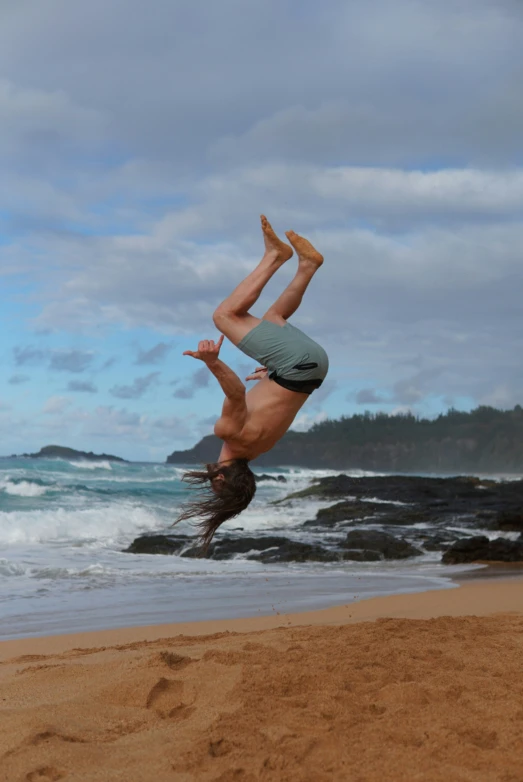 a man doing a handstand on the beach