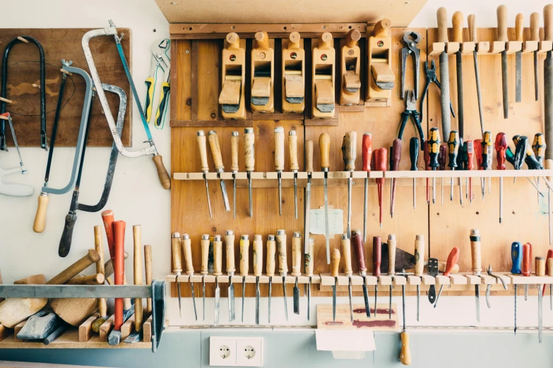 tools are hanging on wooden shelves with hooks and clamps