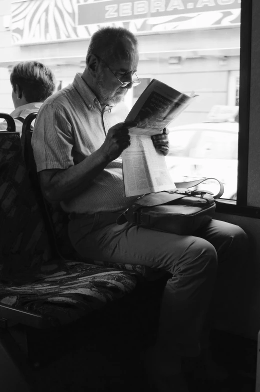 man sitting on a bus reading the paper