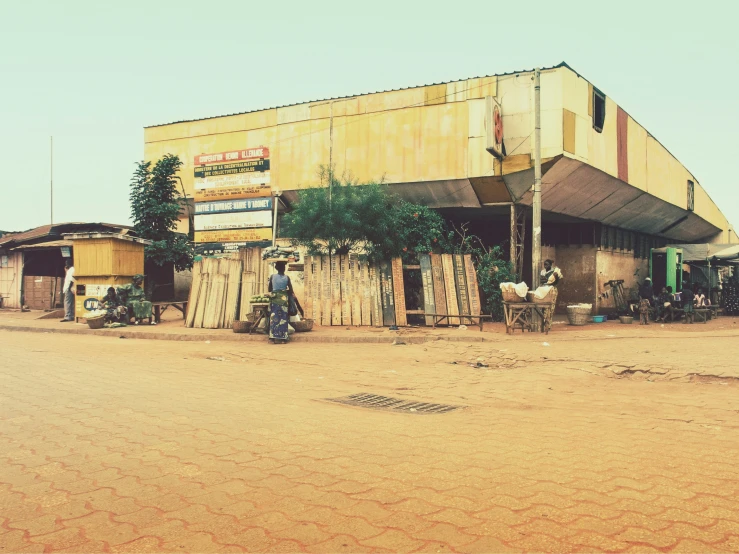 a dirt road next to buildings with cars parked outside