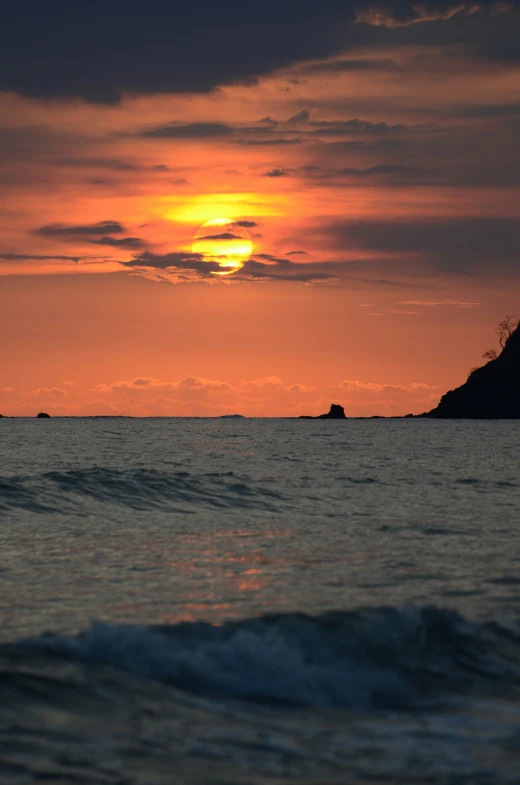 sunset over the ocean as waves come in