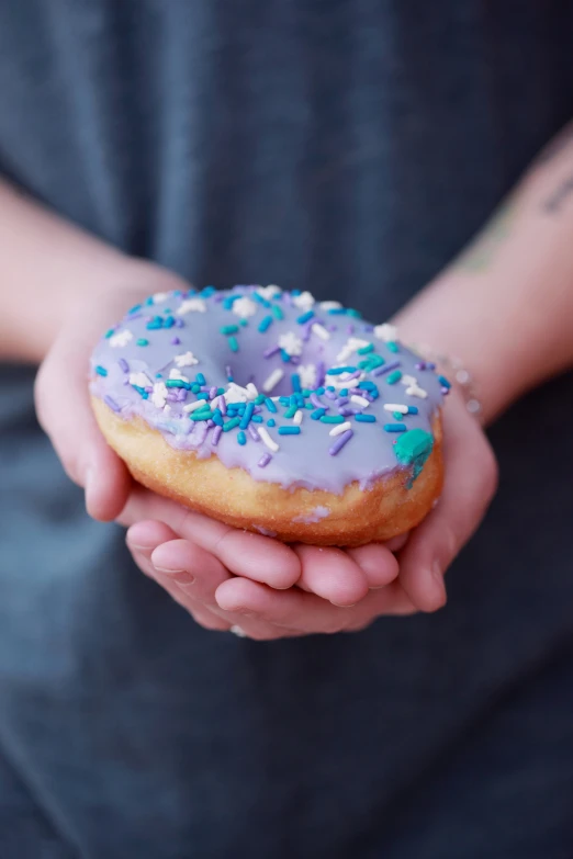 the person is holding a donut covered in blue and white frosting