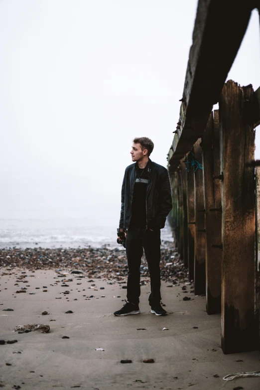 a man standing by a wooden bridge at the beach