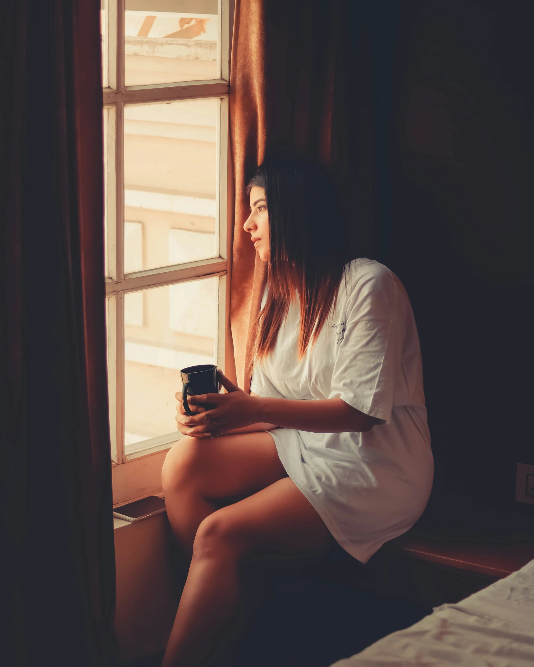 a woman looking out of the window at her cell phone