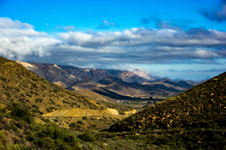 a valley in the mountains with hills and clouds