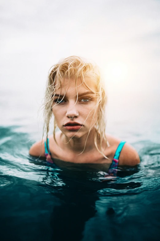 a young lady standing in the water with her hand on her hip