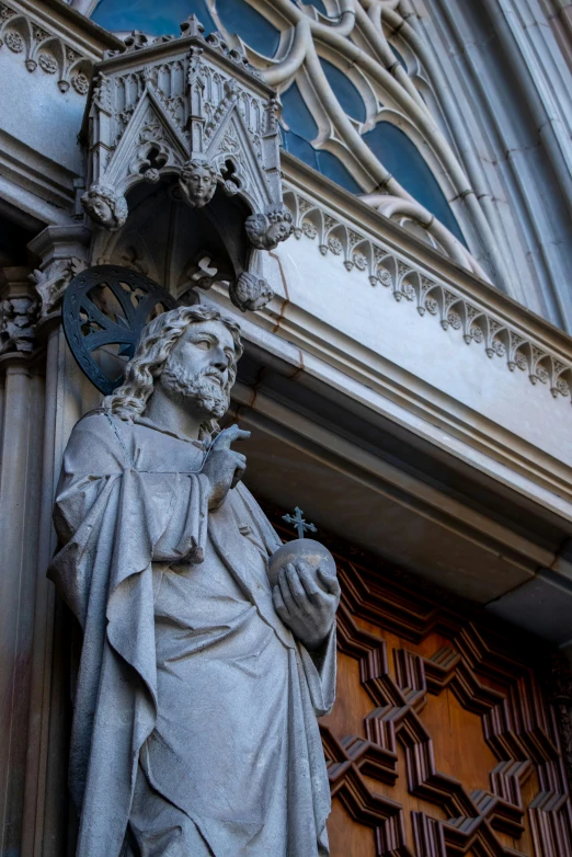 a statue of a man holding a clock on the outside of a building