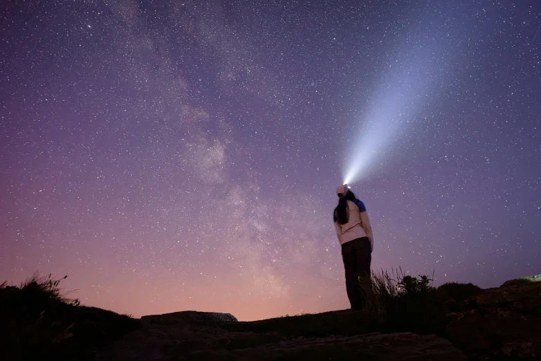 person holding an flashlight looking up into the night sky