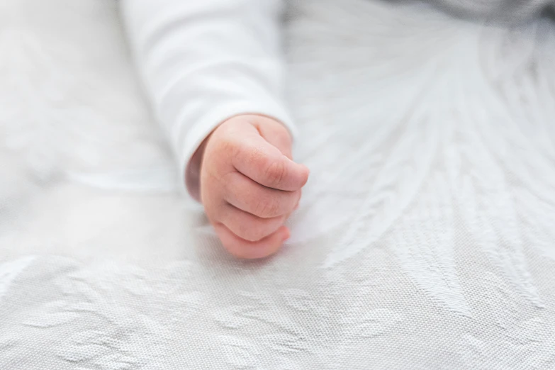 someones arm laying on a blanket with their hands together