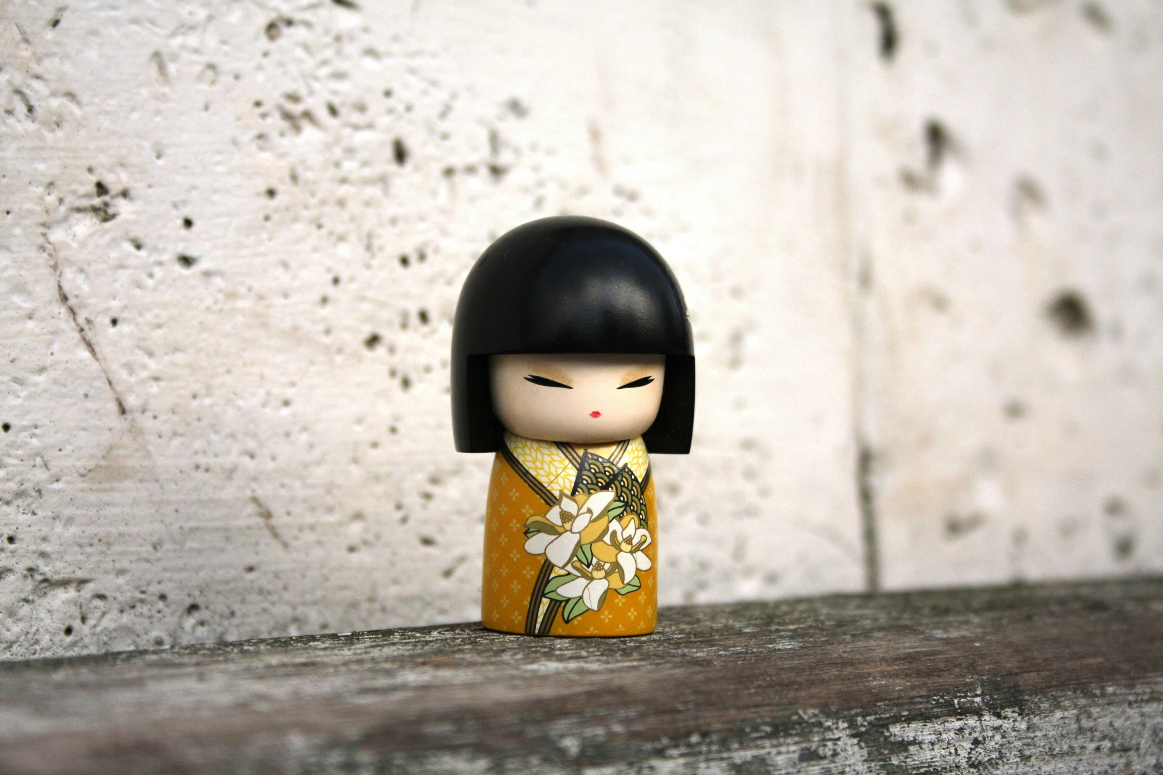 a small doll sitting on top of a stone wall