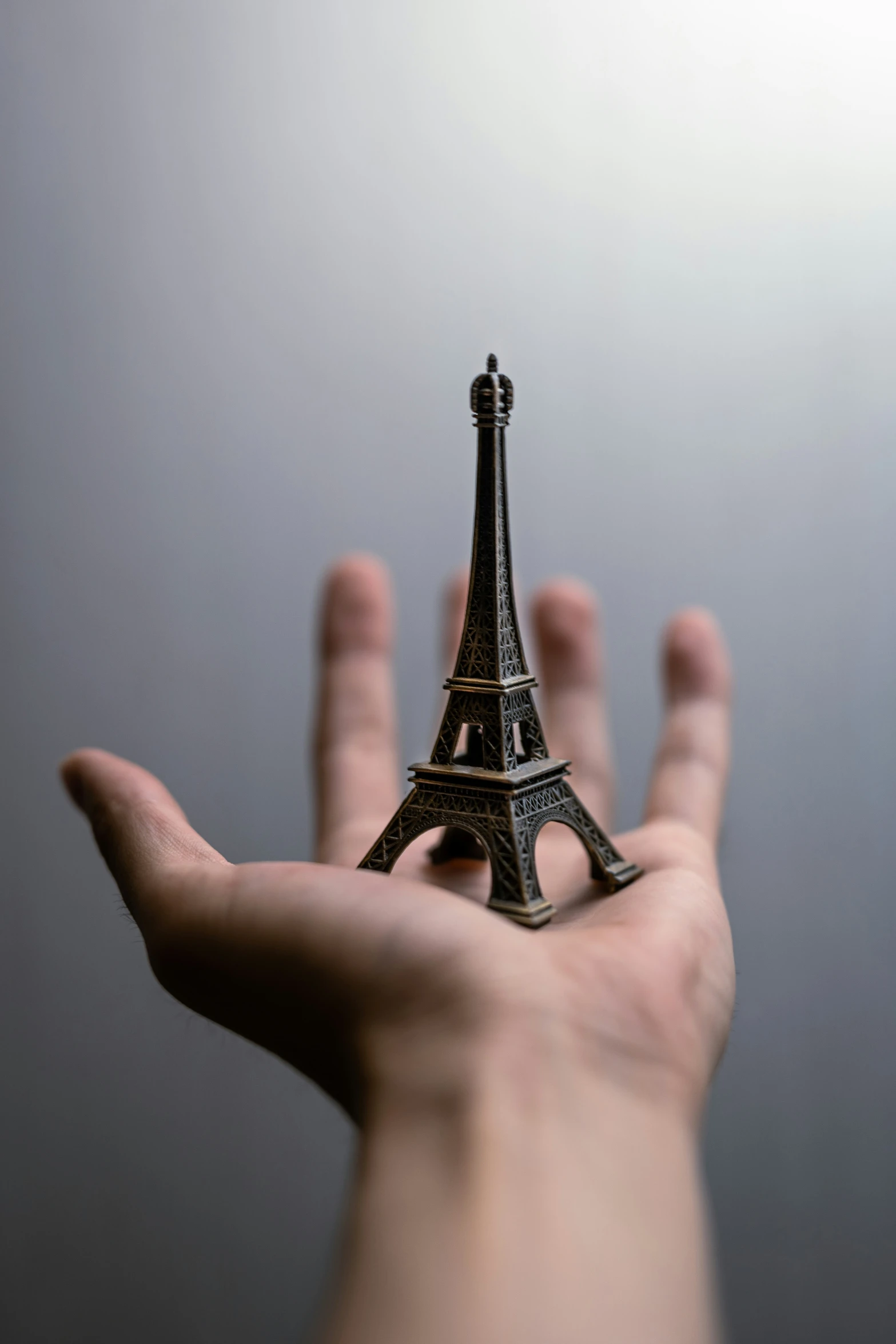 a miniature model of the eiffel tower is held in front of someone