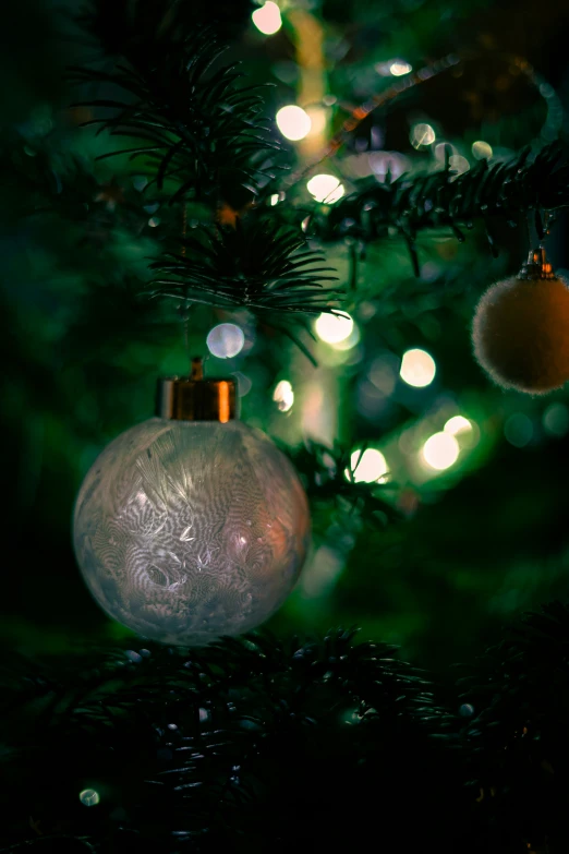 a clear ball ornament on the tip of a christmas tree