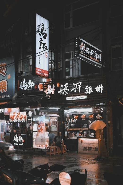 city street at night with umbrellas and advertit on buildings