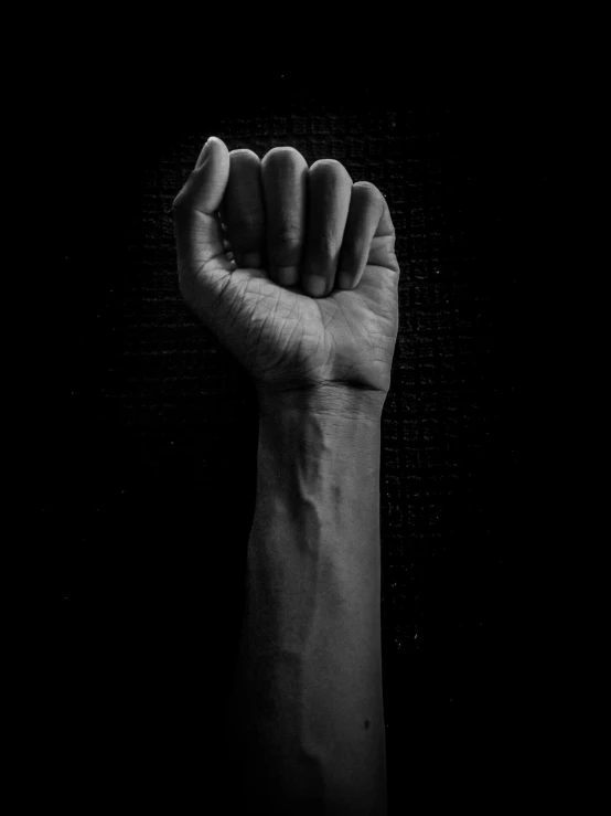 an arm with a raised fist up in the dark