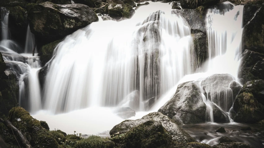 a group of water cascading down a cliff near rocks