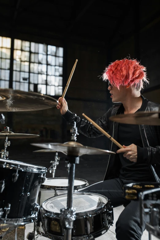 a man with a red wig plays the drums