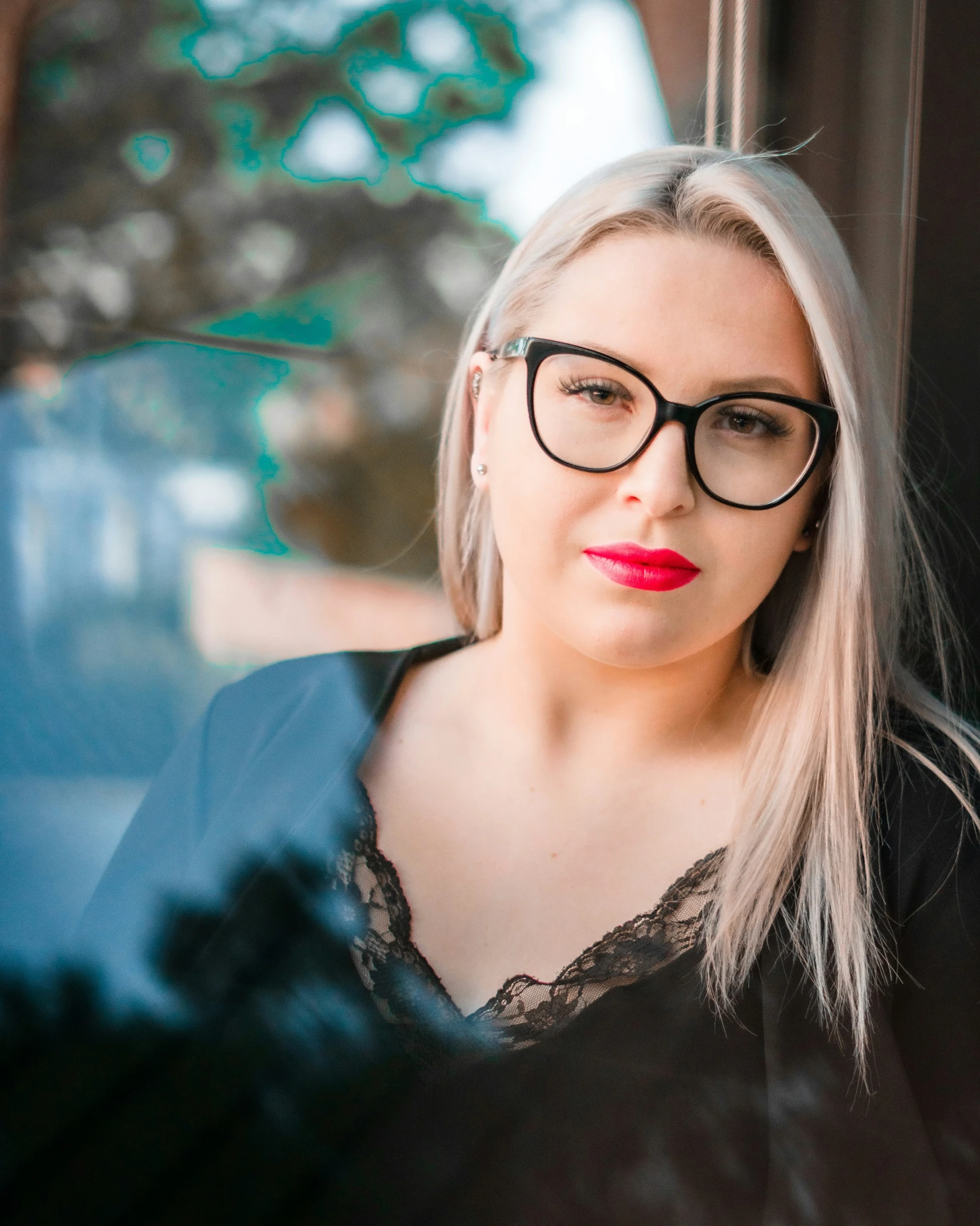 a woman with glasses and bright red lipstick poses for a picture